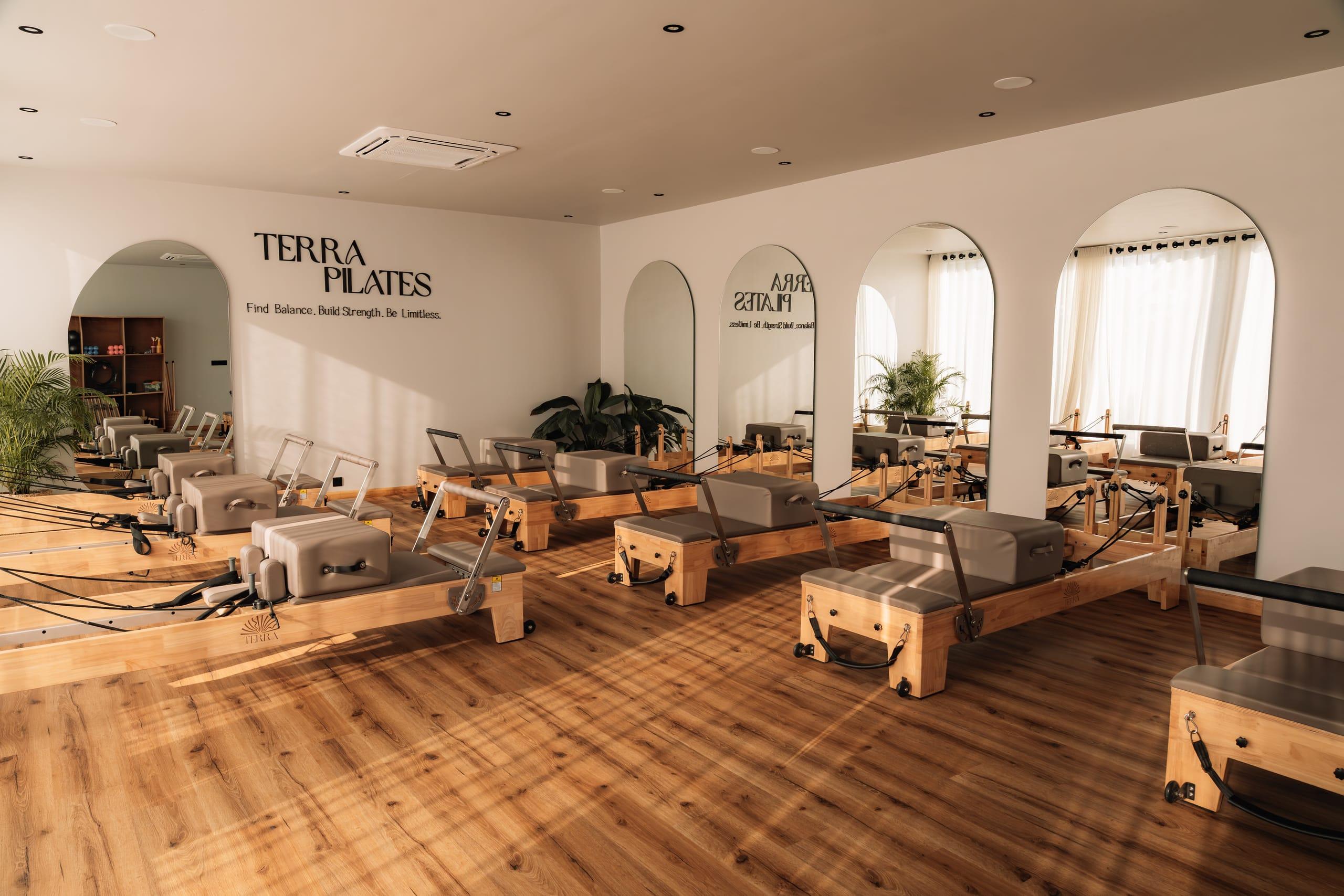 Terra Pilates reformer studio in golden light, arched mirrors along the wall
